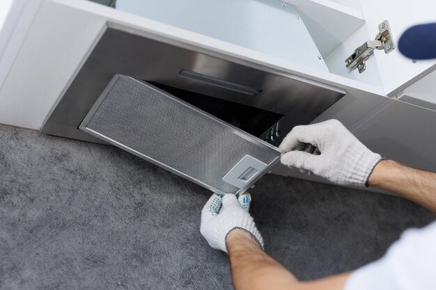 mans hands removing filter from cooker hood cleaning replacing filter kitchen hood