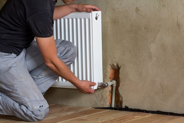 professional plumber worker installing heating radiator brick wall empty room newly built apartment house construction maintenance repair concept 127089 6411